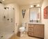 Modern bathroom with elegant wooden cabinetry, sleek glass shower, and artistic decor, offering a serene and stylish retreat.