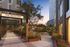 Charming courtyard view with modern architecture, lush greenery, and cozy outdoor seating, perfect for relaxation at sunset.