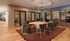 Chic modern meeting room with stylish round table, plush green chairs, and elegant ceiling decor.