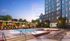 Luxurious outdoor pool area with stylish loungers, vibrant greenery, and a large screen, creating an inviting relaxation spot during sunset.