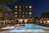 Luxurious apartment complex at night showcasing a vibrant pool area with stylish loungers, a cozy fire pit, and elegant lighting.