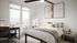 Bright and modern bedroom with large windows, stylish d&eacute;cor, a cozy bed, and a functional workspace offering stunning city views.