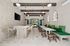 Chic communal space with modern bar seating, cozy green cushioned benches, and elegant arched windows.