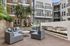 Chic outdoor patio with modern seating, lush greenery, and a sleek linear fireplace, perfect for relaxation and entertaining.