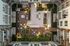 Aerial view of a beautifully landscaped apartment courtyard featuring modern seating areas, lush greenery, and ambient lighting for a serene, urban oasis.