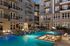 Luxurious apartment complex featuring a stunning illuminated pool area with lounge chairs, perfect for relaxation and social gatherings.