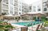 Contemporary apartment complex with a luxurious swimming pool, stylish lounge chairs, and elegant palm trees, offering a relaxing resort-like atmosphere.