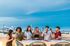 Vibrant rooftop gathering at sunset featuring friends enjoying drinks with a stunning cityscape backdrop.