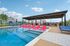 Inviting outdoor swimming pool with vibrant pink and blue lounge chairs, covered seating area, and scenic surroundings, perfect for relaxation and enjoyment.