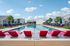 Luxurious outdoor swimming pool with vibrant lounge chairs and umbrellas, surrounded by modern cottages under a clear blue sky.