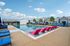 Luxurious outdoor pool area with vibrant lounge chairs, surrounded by modern homes under a clear blue sky.