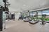 Modern fitness center with state-of-the-art equipment, including treadmills, exercise bike, and weightlifting station, featuring bright natural lighting and spacious layout.