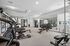 Modern apartment gym with state-of-the-art equipment, featuring cardio machines, weight benches, and a mirrored wall for an inviting workout experience.