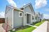 Charming modern house with elegant gray siding, well-maintained green lawn, and inviting pathway under a sunny blue sky.