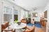 Bright and inviting living area with natural light pouring through large windows, stylish modern furniture, and a cozy ambiance accented by vibrant decor and a lush green view.
