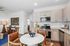 Modern open-plan kitchen and dining area featuring sleek cabinetry, stainless steel appliances, and a stylish round dining table with leather chairs.