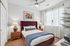 Elegant bedroom with a plush maroon headboard, stylish nightstands, and soothing natural light through sheer curtains.