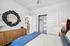 Inviting bedroom with modern decor, featuring a large black circular mirror, elegant wooden sideboard, and spacious closet with sliding doors.