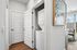 Modern apartment hallway featuring in-unit laundry with sleek stackable washer and dryer, leading to a bright living area with floor-to-ceiling windows.