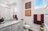 Modern bathroom with granite countertop, sleek cabinetry, vibrant artwork, and stylish tile accents.
