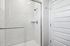 Elegant bathroom with a modern glass shower enclosure, featuring sleek white subway tiles and a chrome shower fixture.