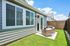 Charming outdoor seating area with cozy wicker chairs on a sunny patio, surrounded by lush green grass and a wooden privacy fence.