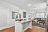 Bright and modern open-concept living space featuring a sleek kitchen island, contemporary art, and a cozy living room with elegant hardwood floors.