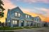 Charming suburban homes with modern blue and white facades at sunset, featuring inviting porches and manicured lawns.