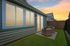 Charming backyard view of modern house with cozy patio seating and privacy fence at sunset.