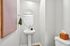 Chic bathroom with a modern pedestal sink, elegant round mirror, and tasteful wall art.