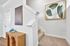 Bright and modern entryway featuring elegant art on the walls, a chic wooden console, and plush carpeted stairs leading to the upper floor.