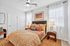 Inviting bedroom with elegant decor, featuring a plush bed adorned with patterned pillows, ambient lighting, and modern art.
