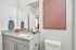 Modern bathroom with sleek granite countertop, stylish gray cabinets, and vibrant wall art adds character.