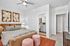 Chic bedroom with elegant decor, featuring a cozy bed, modern ceiling fan, stylish artwork, and an ensuite bathroom for added convenience.