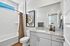 Modern bathroom with elegant granite countertop, stylish artwork, and natural light streaming through a large window.