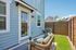 Charming backyard patio with cozy wicker seating, lush green lawn, and a modern outdoor light fixture.