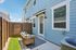 Charming outdoor patio with comfortable seating, perfect for relaxing, framed by stylish blue siding under a bright sky.