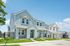 Charming suburban duplexes with modern designs, featuring crisp blue and white exteriors, manicured lawns, and bright sunny skies.