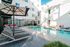 Chic apartment courtyard featuring a pristine swimming pool, modern loungers, and stylish seating with vibrant accents.