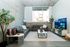 Modern living room with sleek gray sofas, large TV, and abundant natural light, creating a cozy yet stylish entertainment space.