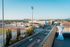Charming balcony view overlooking a vibrant cityscape with a modern sports complex and distant scenic hills.