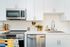 Modern kitchen with sleek white cabinetry, stainless steel appliances, and vibrant decor accents for a fresh and inviting atmosphere.