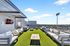 Stunning rooftop terrace with modern outdoor seating, vibrant green artificial turf, and scenic city views, perfect for relaxation and entertainment.