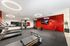 Chic and modern gym featuring state-of-the-art equipment, vibrant red accent wall, and stylish circular lighting.