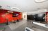 Modern fitness room featuring sleek exercise equipment, vibrant red tiled wall, and stylish circular lighting for an energizing workout ambiance.