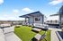 Chic rooftop lounge with modern seating, green artificial turf, and panoramic city views under a stylish pergola.