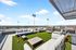 Expansive rooftop terrace with cozy seating and panoramic city views under a clear blue sky.