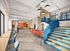 Vibrant modern communal space featuring open seating, colorful couches, and stylish lighting with a unique blue staircase.