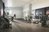 Modern apartment gym with state-of-the-art exercise equipment, sleek wood flooring, and ample natural light through large windows.