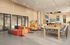 Modern communal area with vibrant seating, large conference tables, and stylish decor, perfect for coworking or social gatherings.